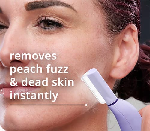 Woman using a sonic dermaplaning tool with LED light in bathroom mirror